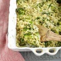 Cauliflower and broccoli casserole served in a white dish with a wooden spoon.