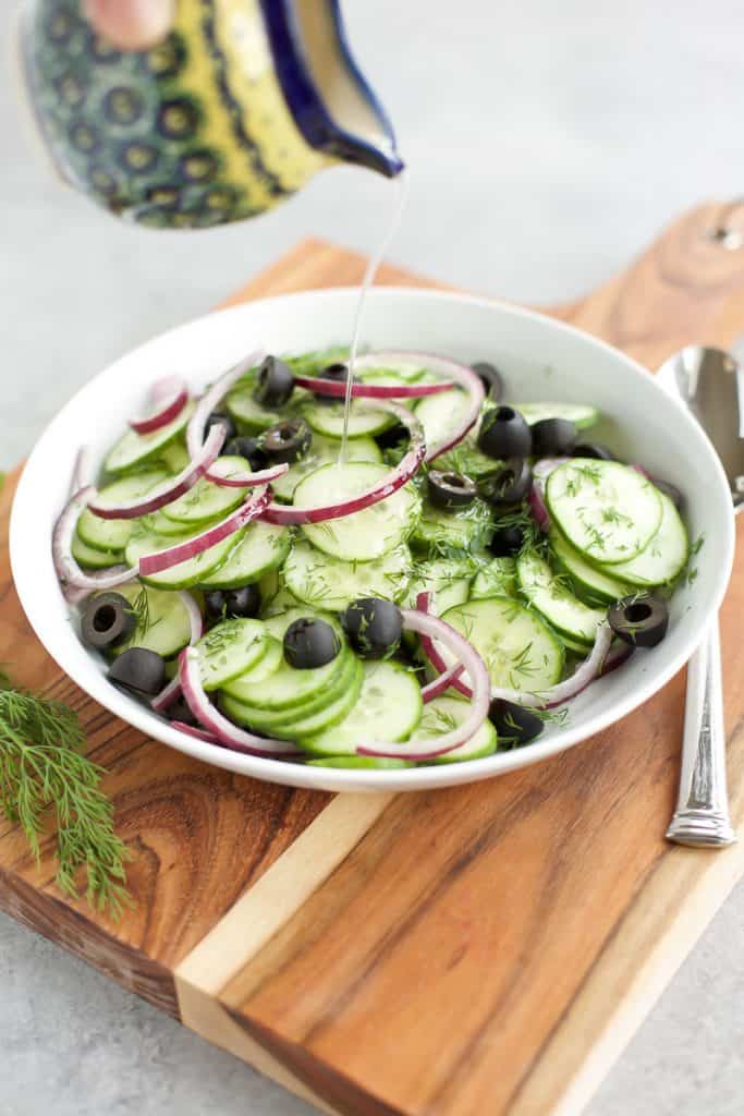 cucumber salad in a white bowl with dressing 