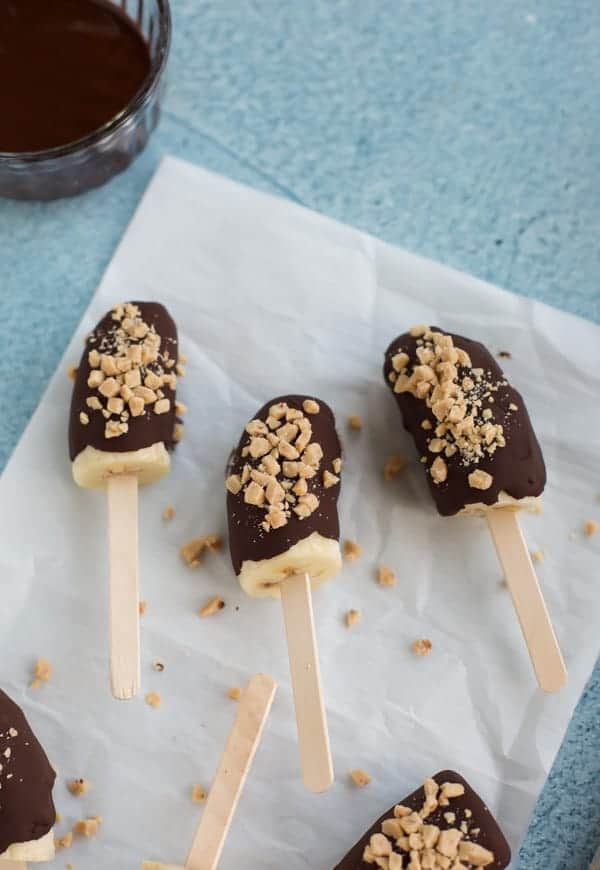 chocolate covered frozen bananas on parchment paper