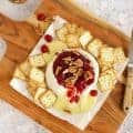 Baked Brie with Cranberry Sauce on a wooden board.