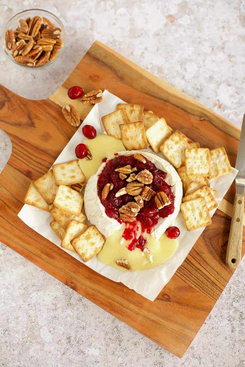Baked Brie with Cranberry Sauce on a wooden board.