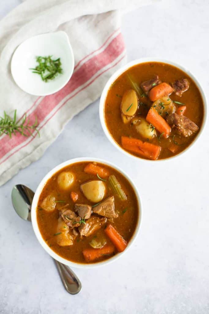 instant pot beef stew in two bowls with a spoon