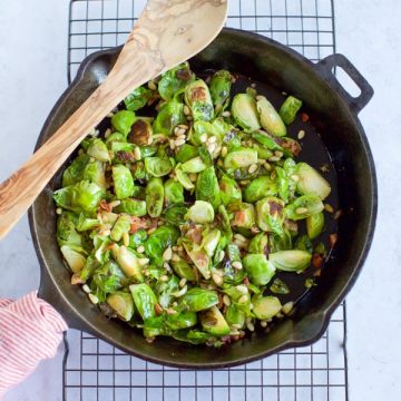 Sauteed Brussels Sprouts in a Skillet with a Wooden Spoon.