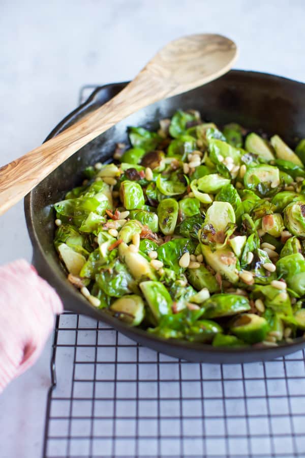 Sauteed Brussels Sprouts in a cast iron pan with wooden spoon