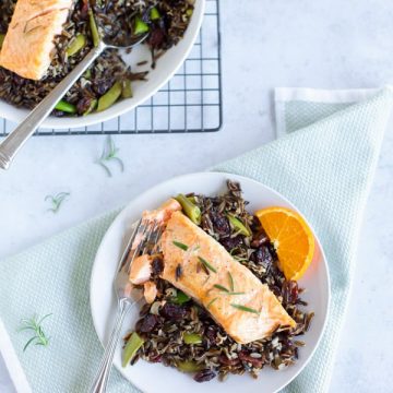 Salmon with wild rice and oranges on a plate, served alongside baked salmon with black rice.