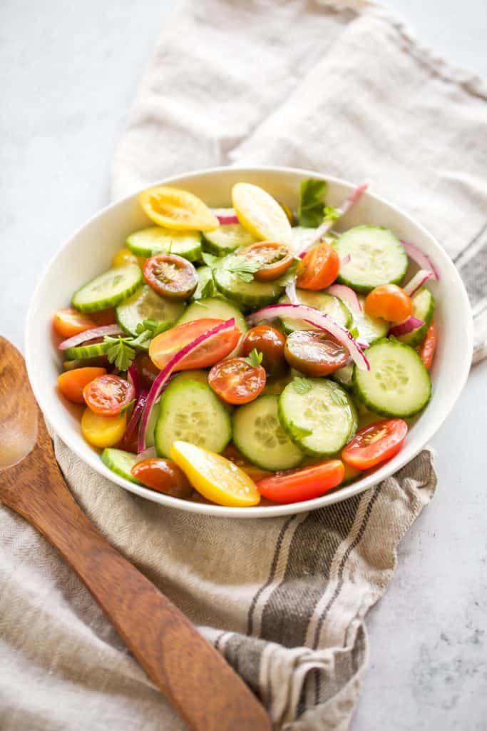 cucumber and tomato salad in a white bowl