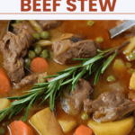 Apple cider beef stew in a pot, topped with a sprig of fresh rosemary.