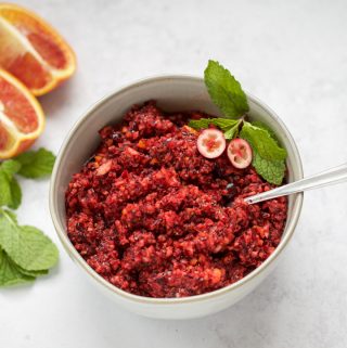 A bowl of grapefruit risotto with a cranberry relish topping and a spoon.