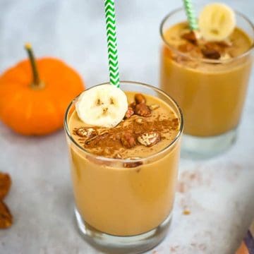 Two glasses of pumpkin smoothie with bananas and a straw.