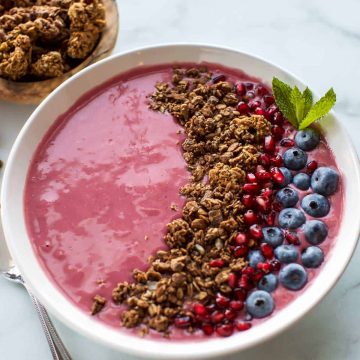 A bowl of blueberry granola with raspberries and granola.