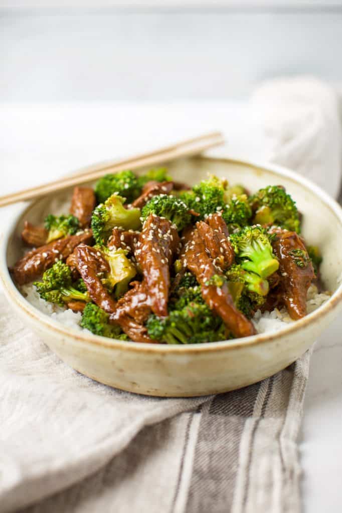 side view of beef and broccoli in a bowl with chopsticks