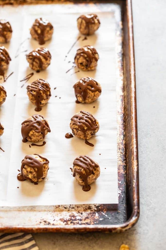 banana bliss balls on a cookie sheet with chocolate drizzle