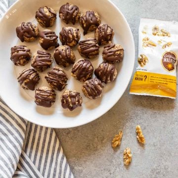 banana bliss balls in a white plate with walnuts on the side