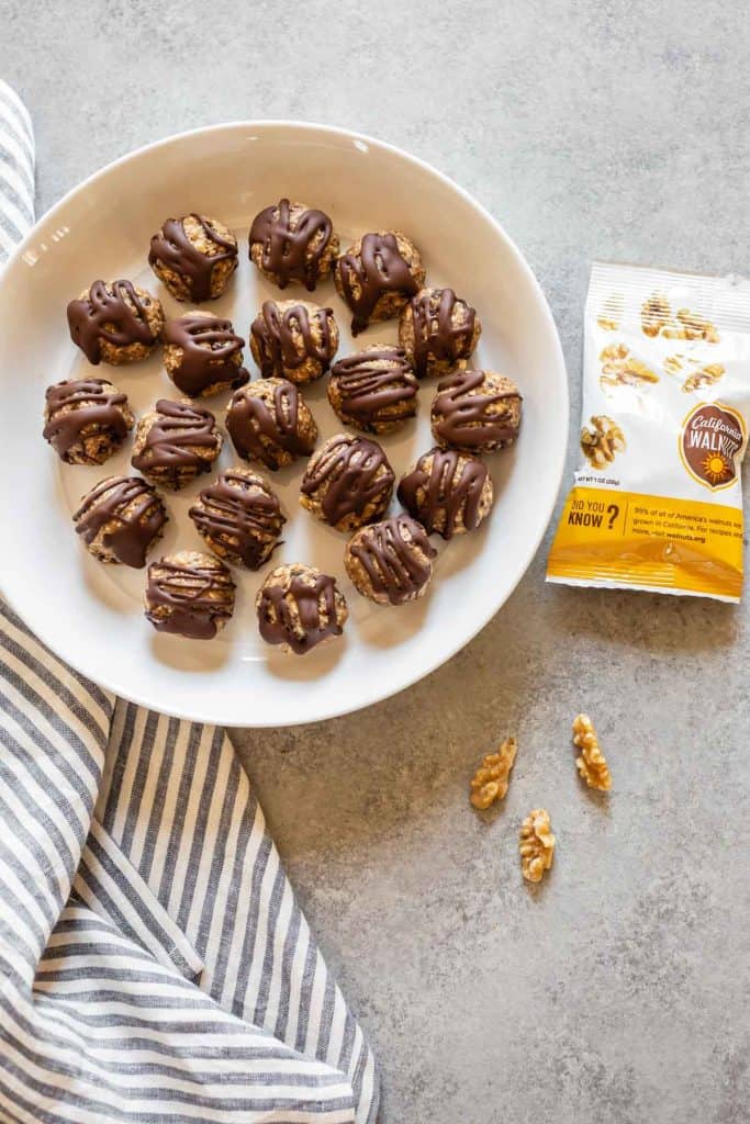 banana bliss balls in a white plate with walnuts on the side