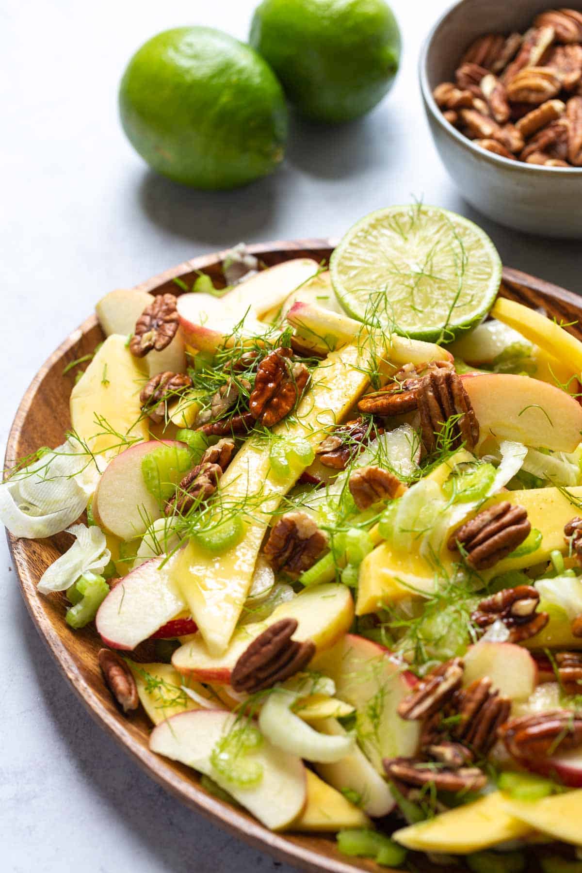 A plate of fruit salad with pecans and limes, accompanied by a refreshing celery salad.