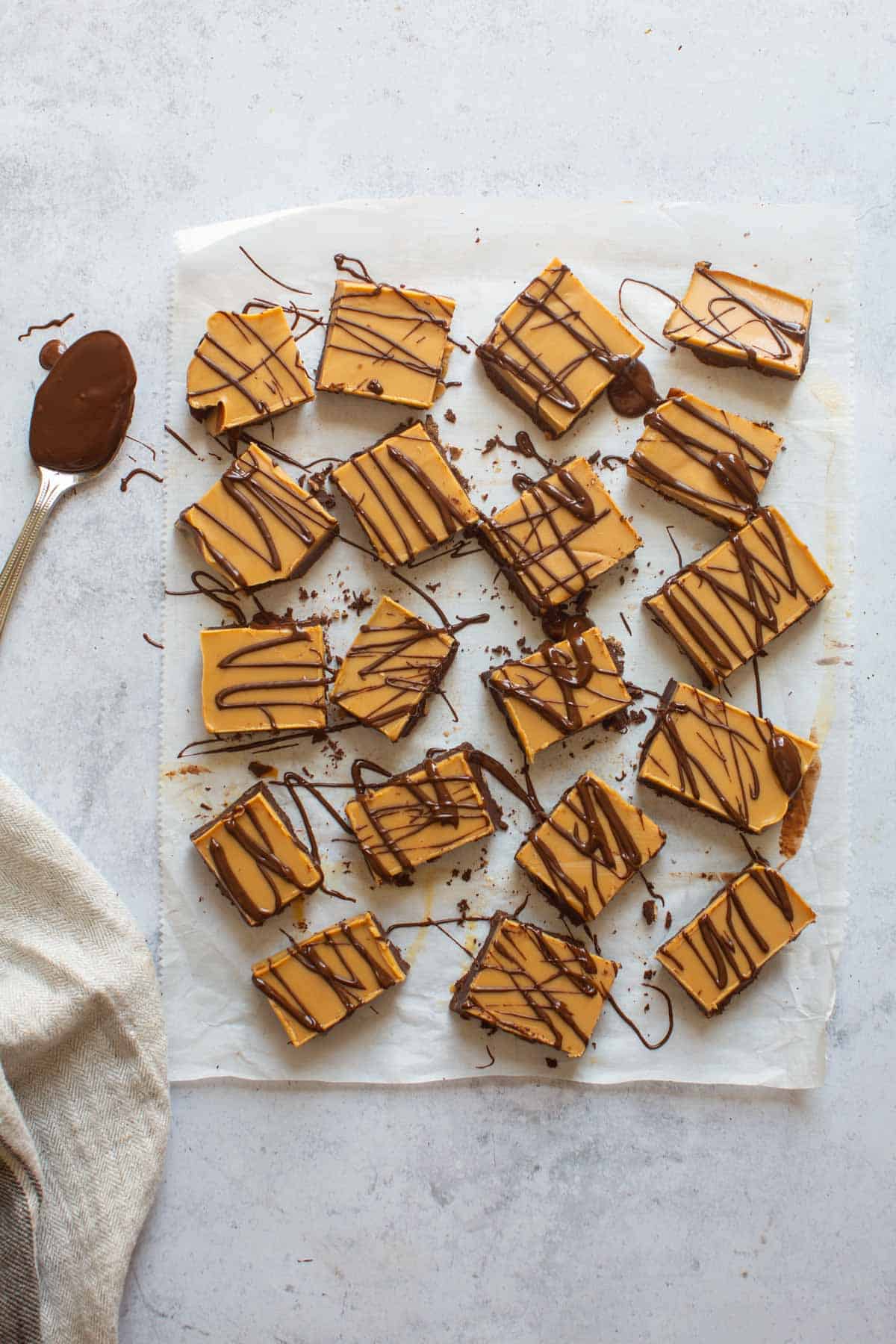 pieces of chocolate peanut butter fudge with chocolate drizzle on parchment paper 
