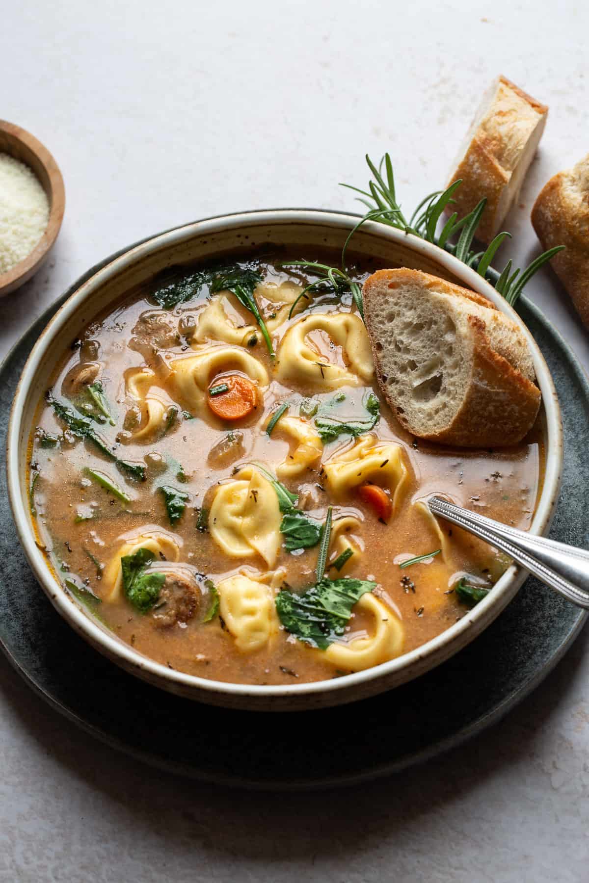 Tortellini Soup with Sausage served in a bowl with bread.