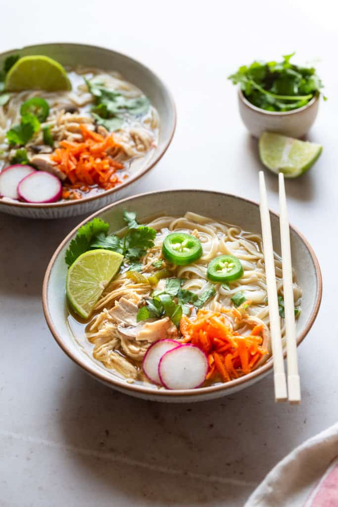 easy chicken pho in two bowls with carrots and radishes