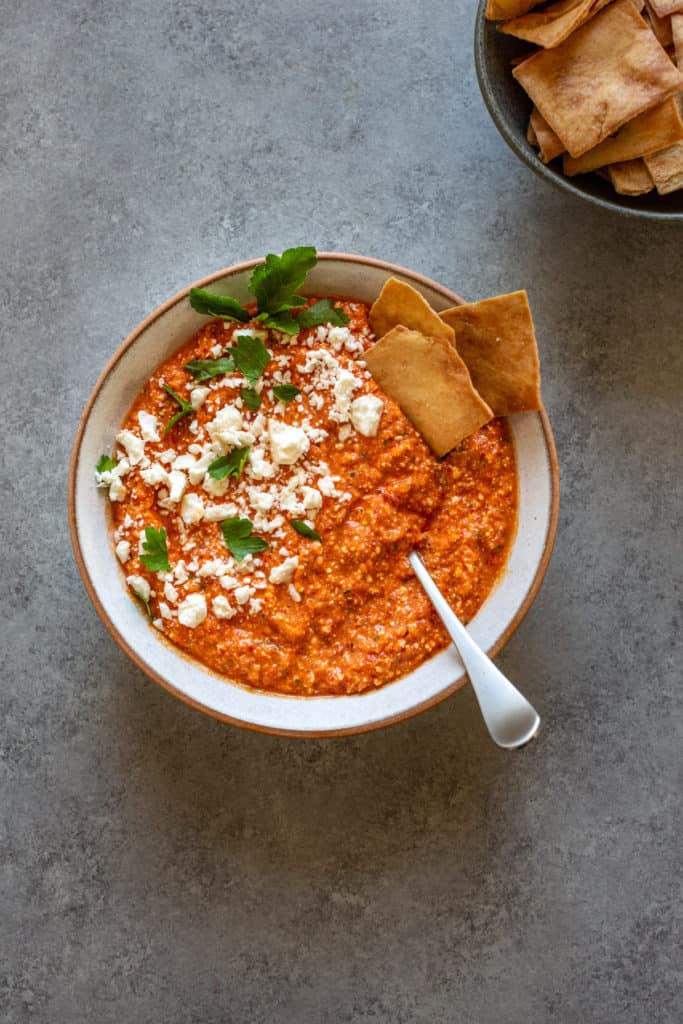 red pepper dip with pita chips in a bowl