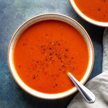 Two bowls of Spicy Tomato Soup on a blue background.