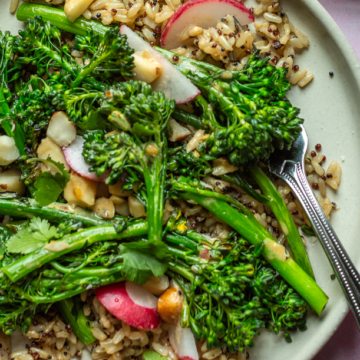 Two plates with broccolini and quinoa salad on them.