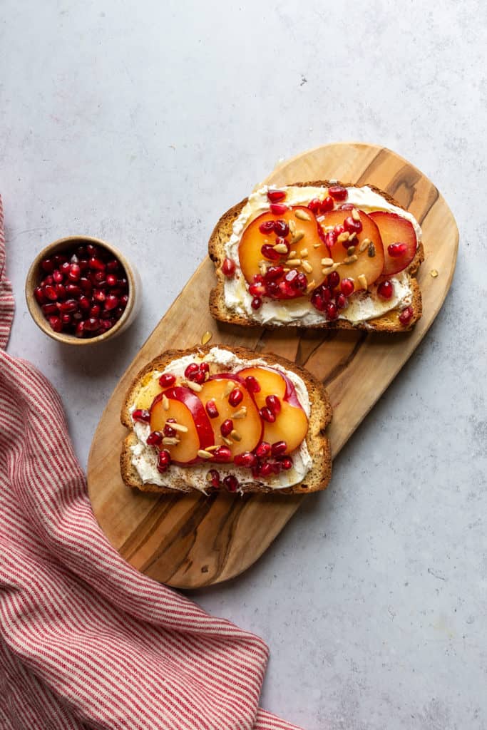 two pieces of toast with plum and pomegranate arils