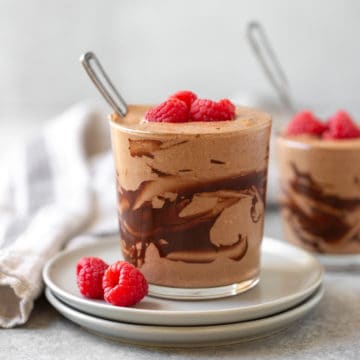 Rich chocolate mousse topped with fresh raspberries on a plate.