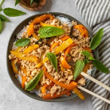 Thai Basil Chicken stir fry with peppers and basil on a plate.