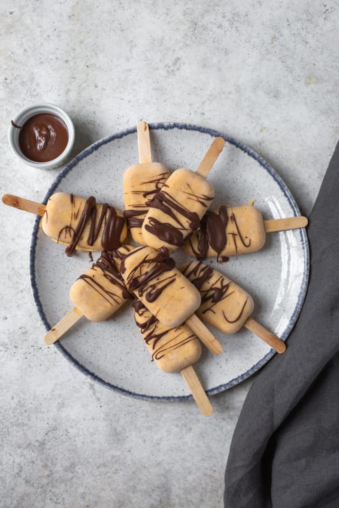 pumpkin popsicles with chocolate drizzle on a plate