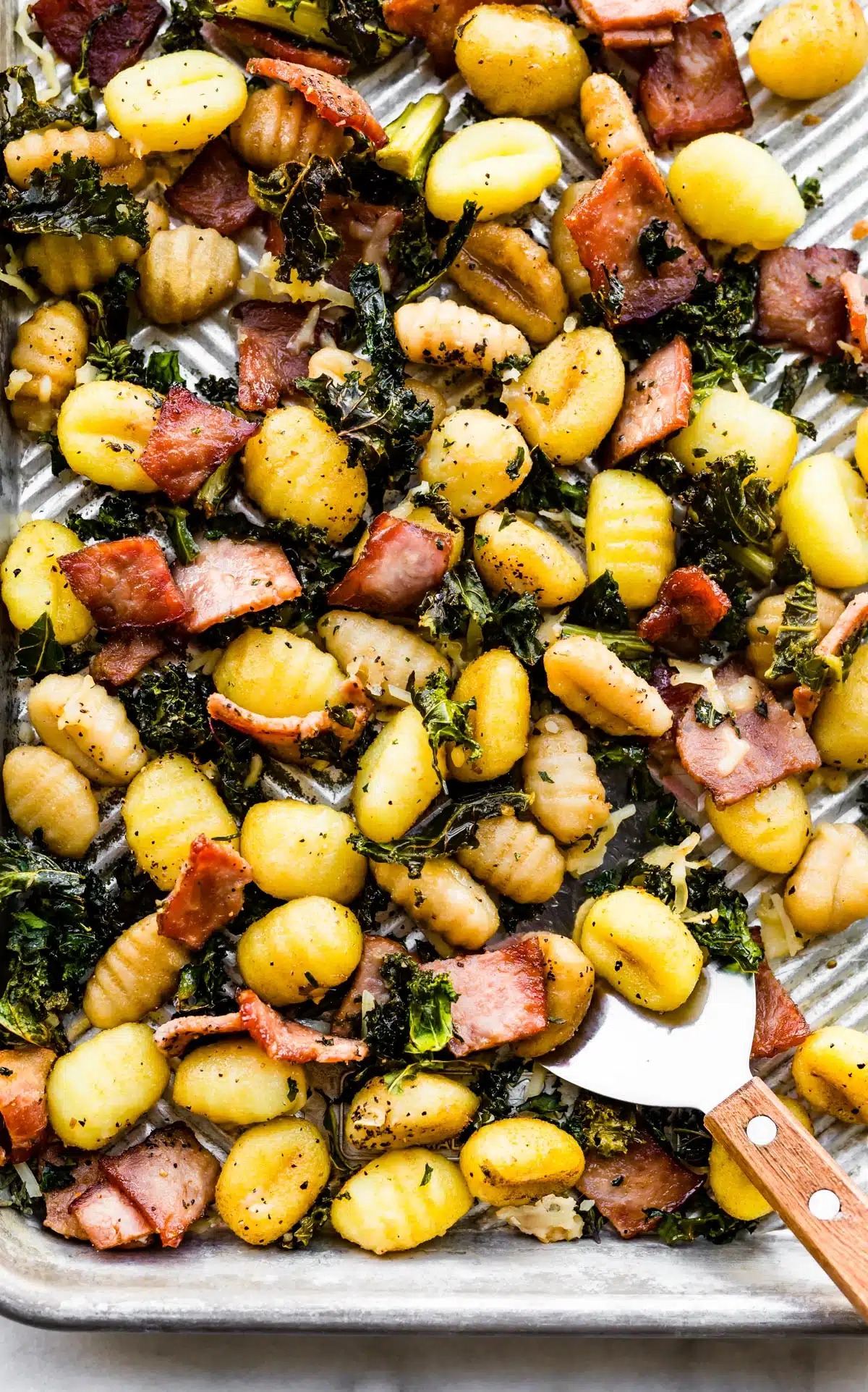 Roasted gluten-free potatoes with bacon and kale on a baking sheet.