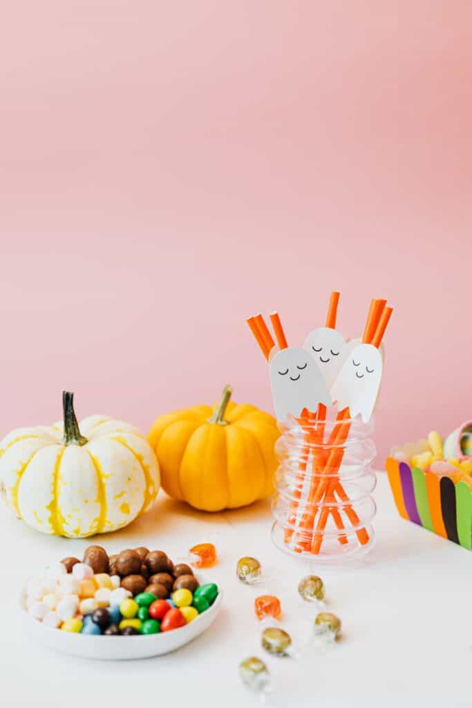 gluten free halloween candy list with candies pumpkins and a glass of straws