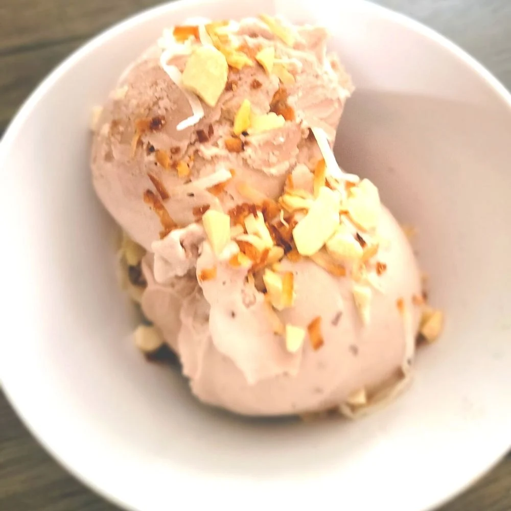 A bowl of ice cream with almonds on top.
