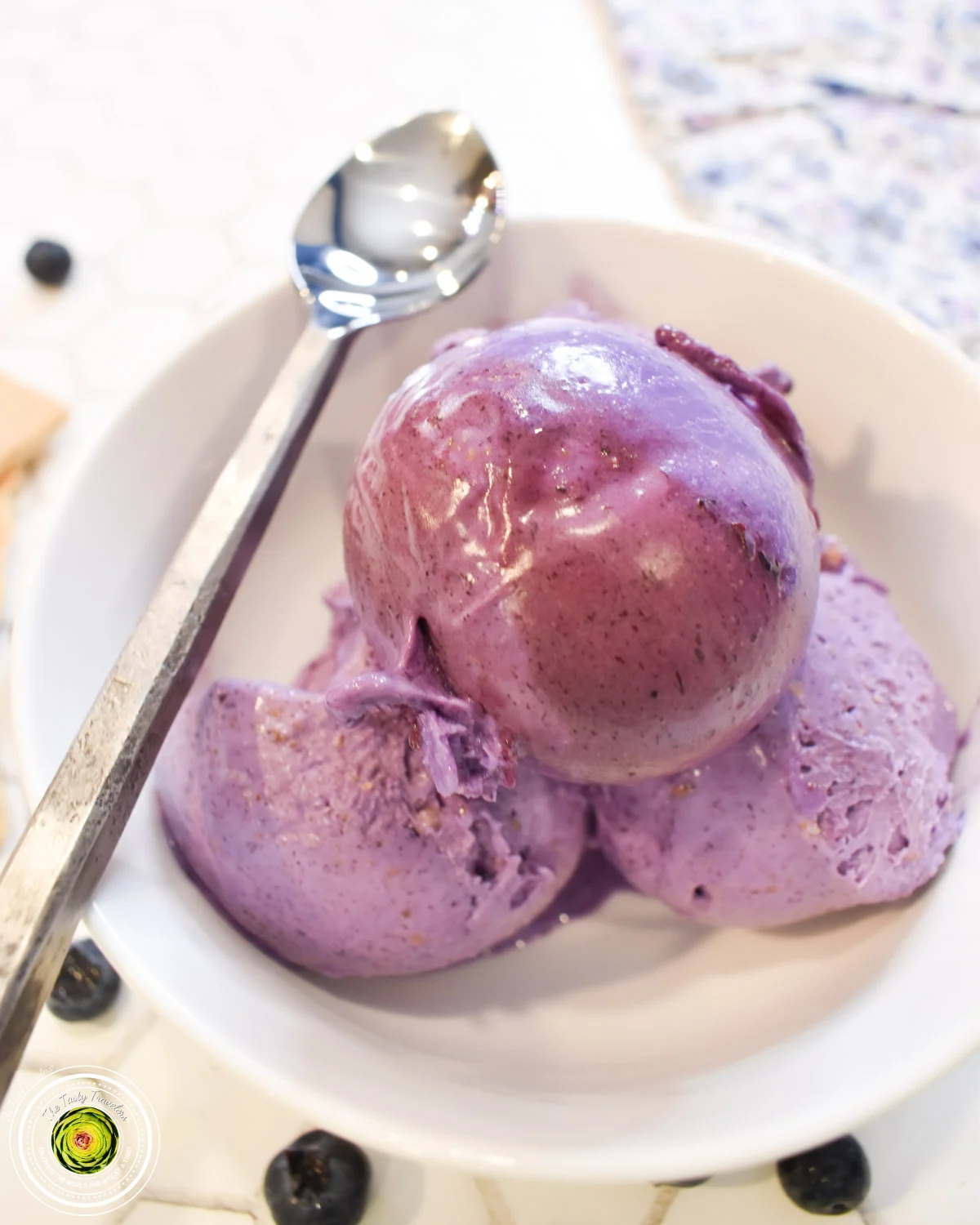 A bowl of blueberry ice cream with a spoon.