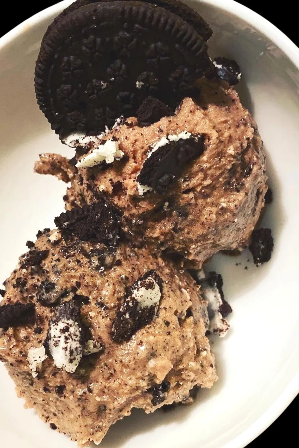 Two scoops of Oreo cookie ice cream in a bowl.