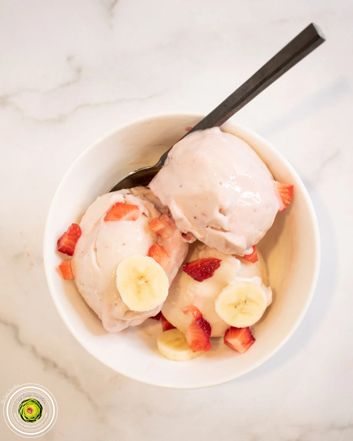 A bowl of ice cream with strawberries and bananas.