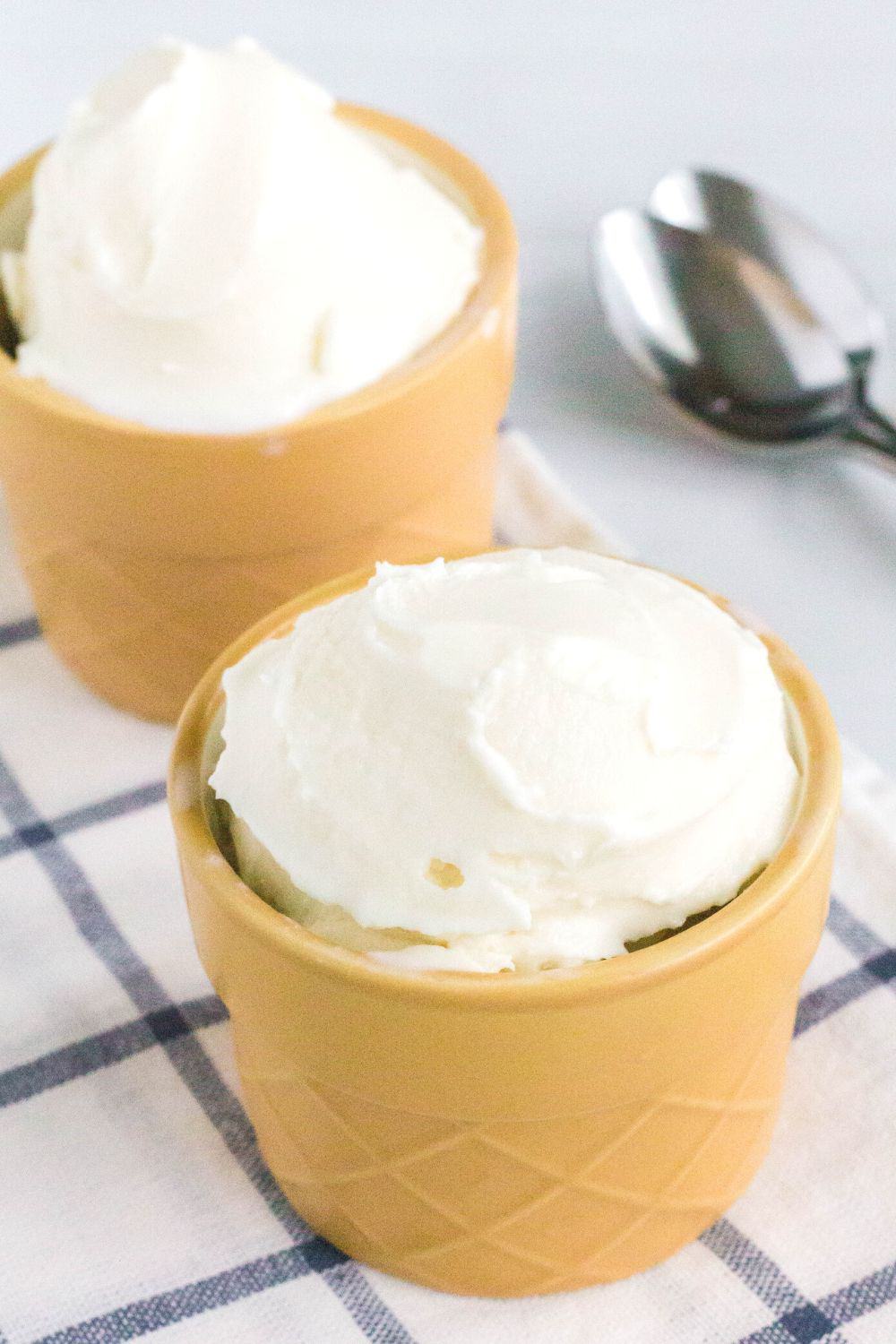 Two yellow bowls with whipped cream in them.