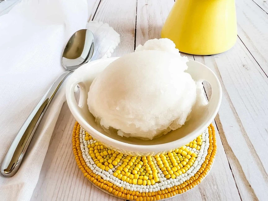 A bowl of lemon sorbet with a spoon on top.