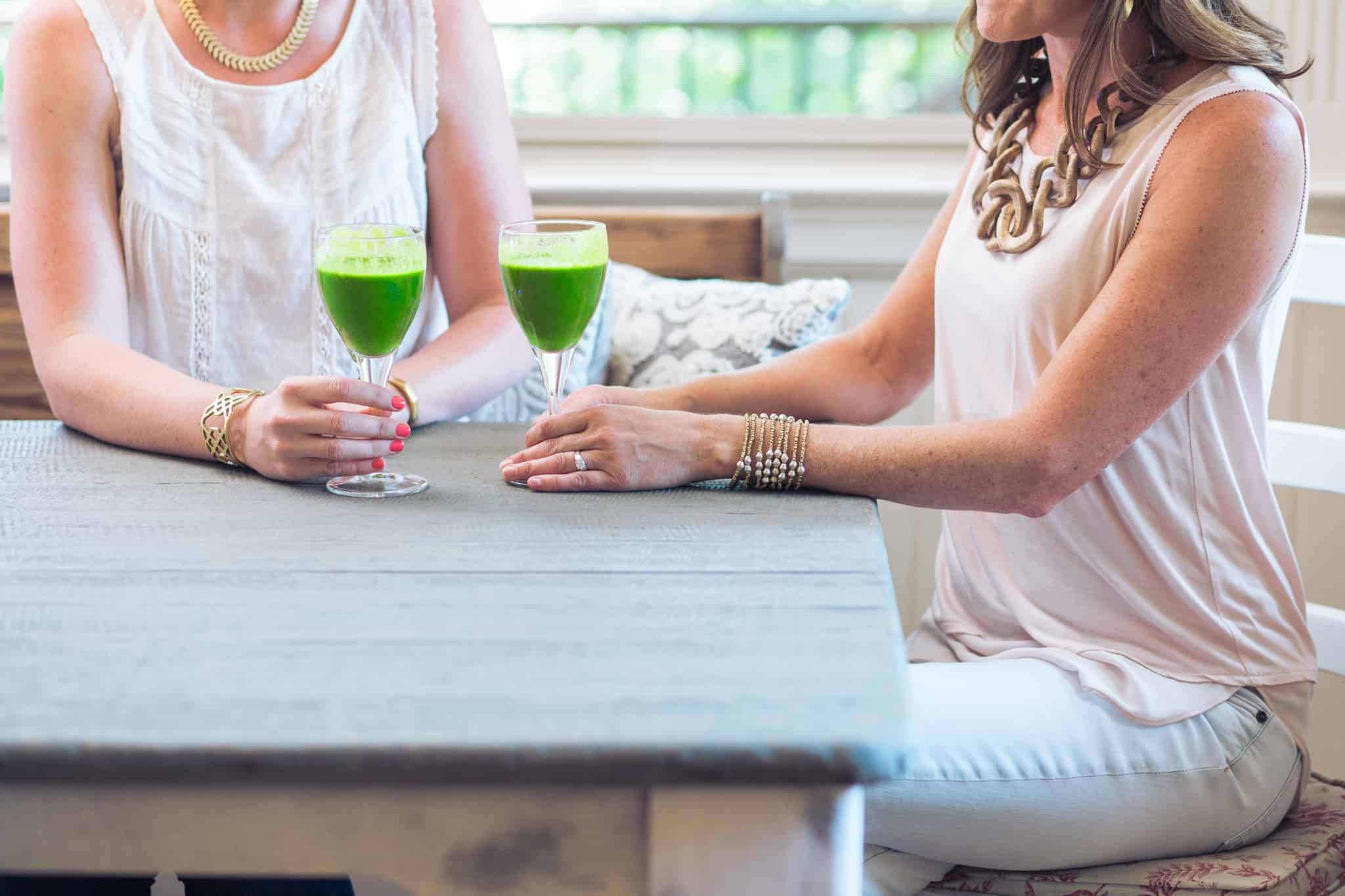 two women drinking green drinks