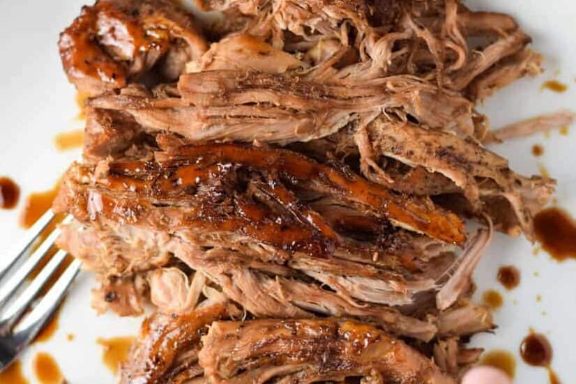 Slow cooker balsamic pork on a white plate with a fork.