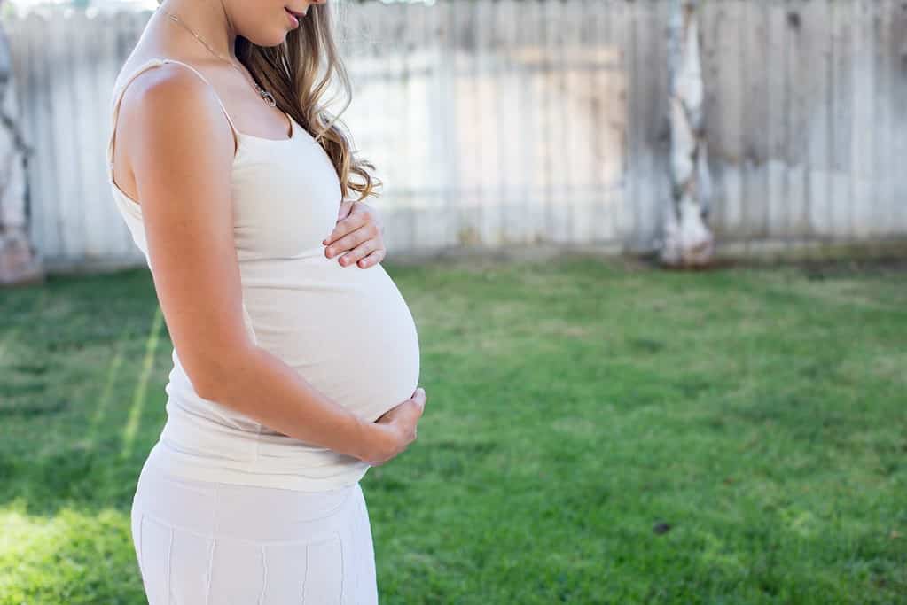 Pregnant woman outside holding her tummy