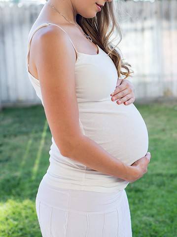 Pregnant woman outside holding her tummy