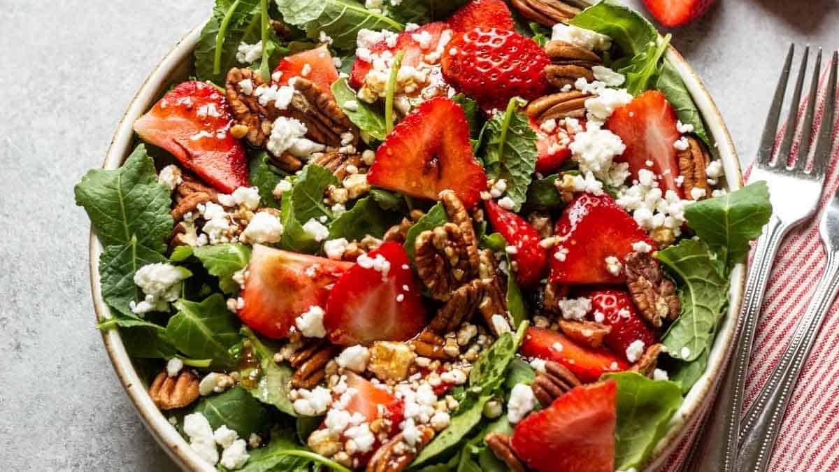 strawberry and pecan salad with feta cheese in a white bowl.