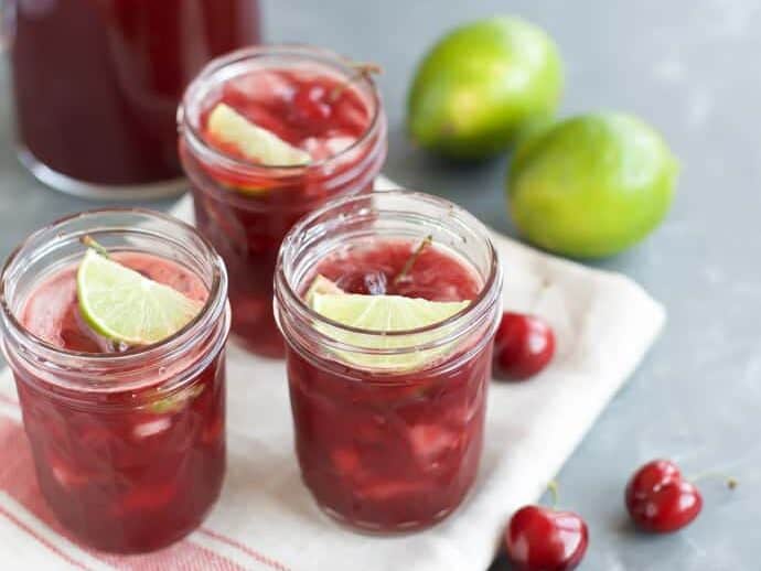 Cherry Margaritas in three glasses with limes