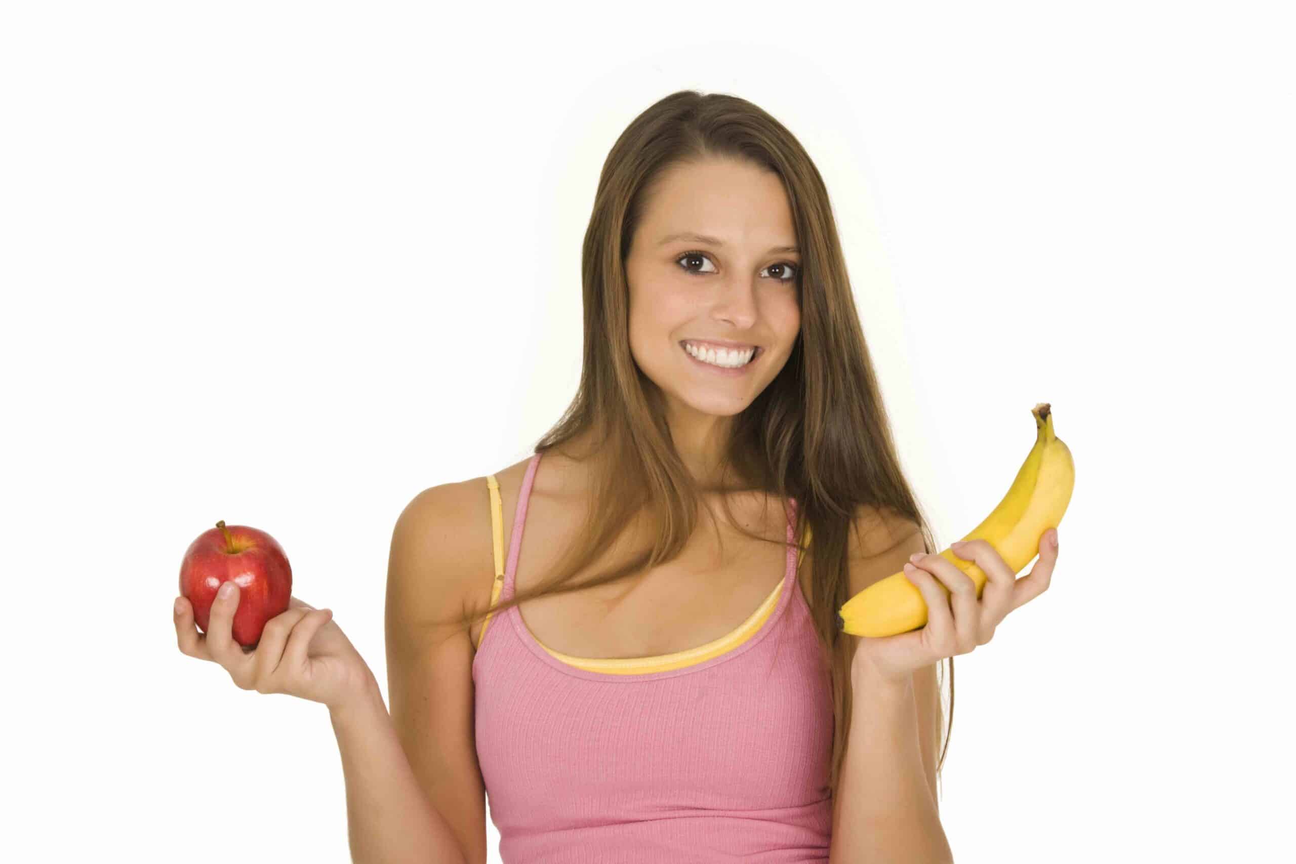 زنی که یک سیب و یک موز در دست دارد و سعی می کند تصمیم بگیرد کدام یک را بخورد