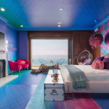 Dive Into an Unforgettable Underwater Adventure With This Mermaid Inspired Blue and Purple Bedroom Featuring a Bed and a Fireplace.