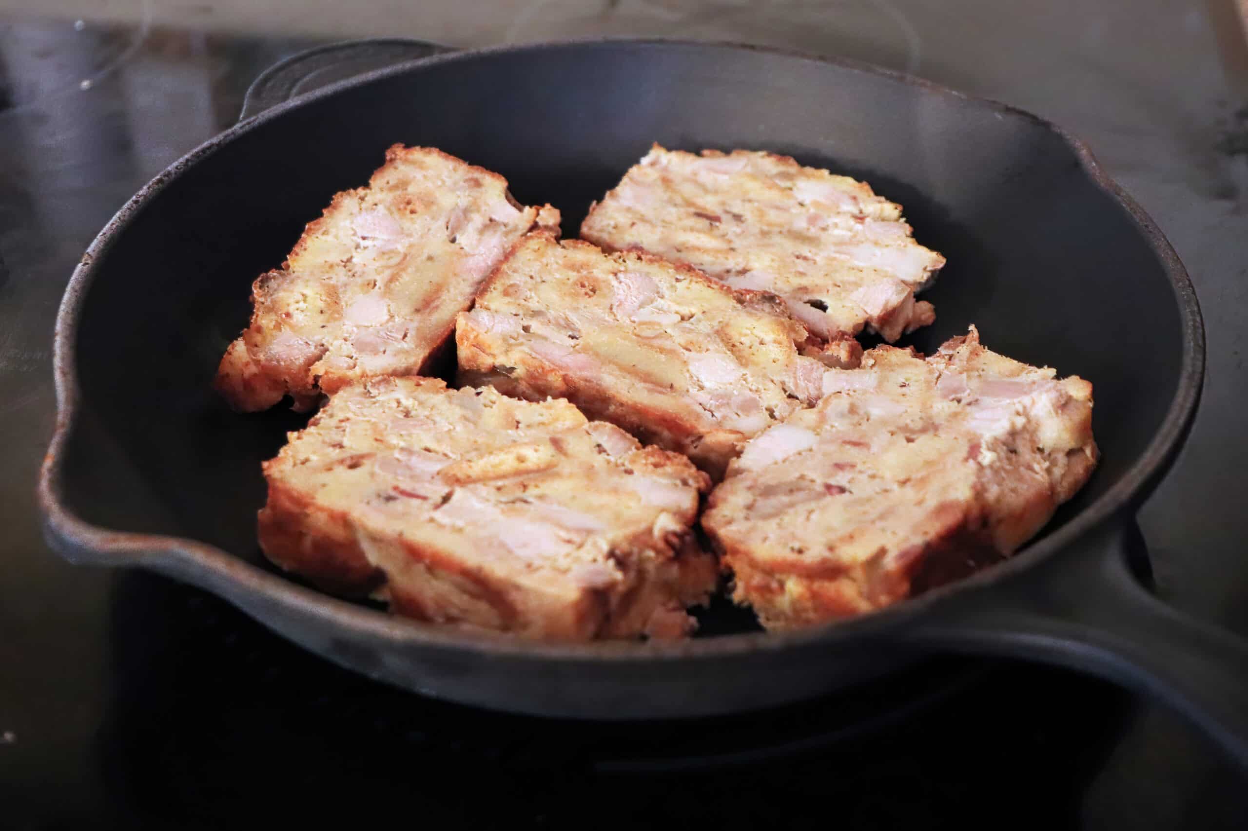 Frying scrapple slices on a cast iron pan.