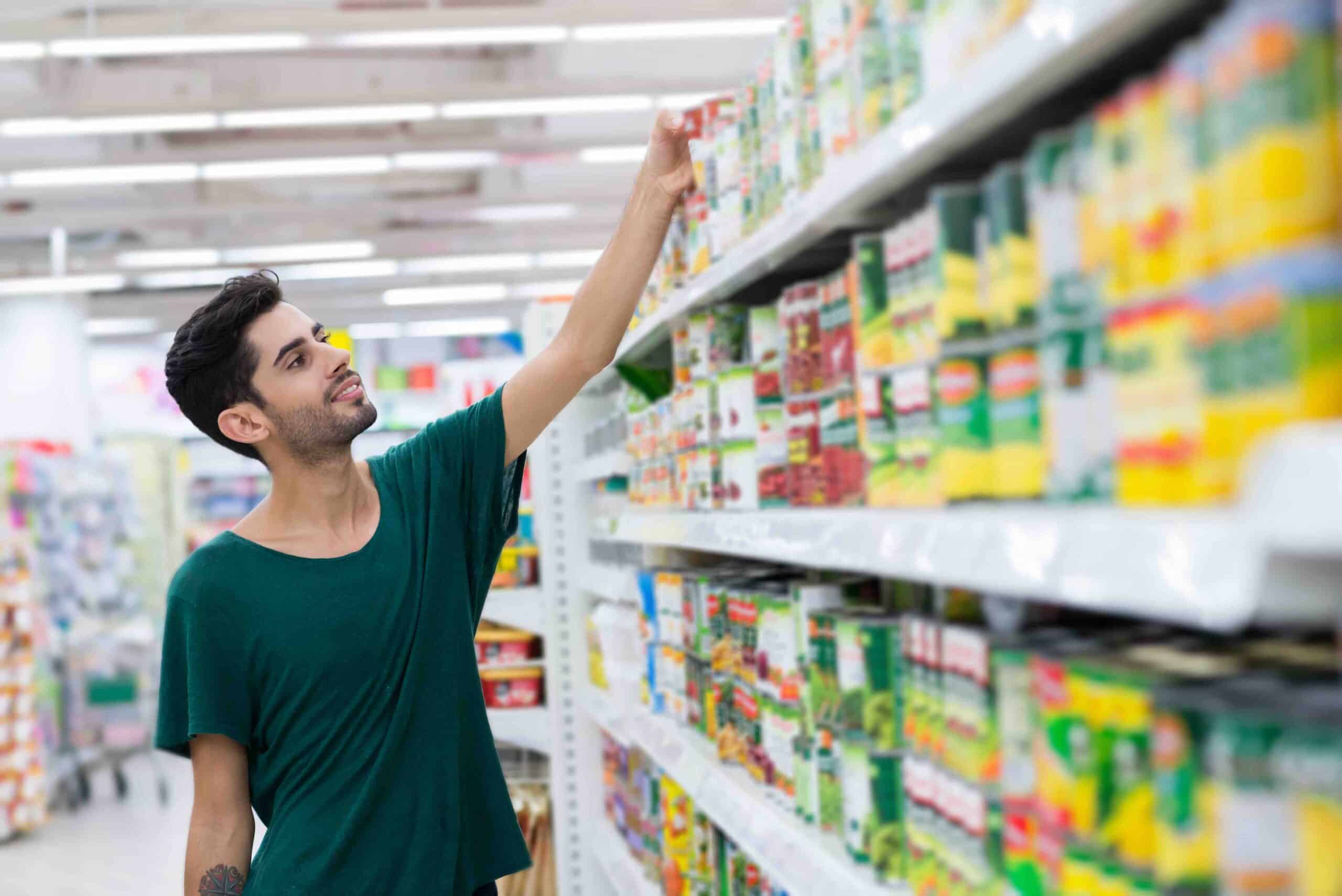 Young customer taking canned food from the shelf in the store