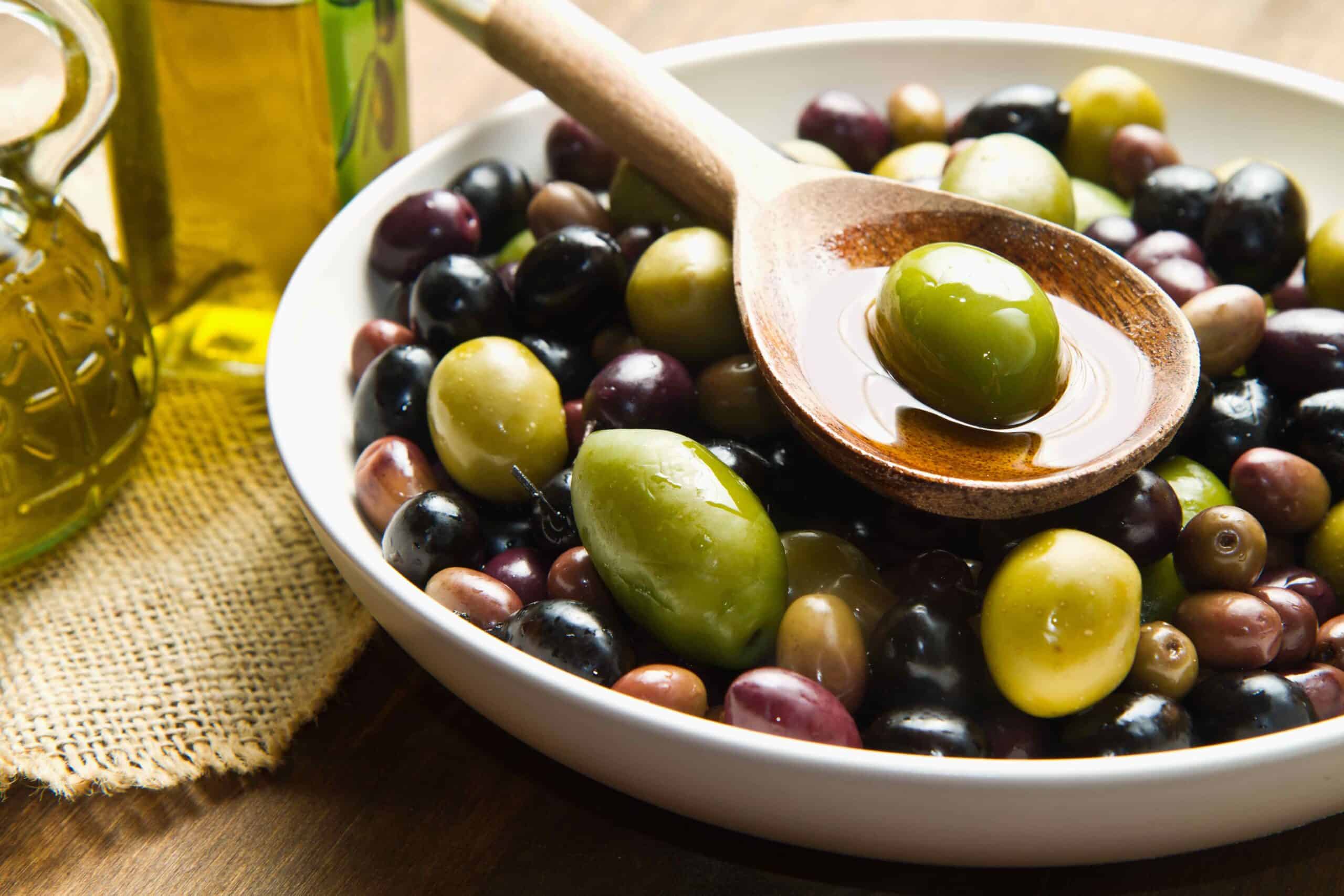 Extra virgin healthy Olive oil with fresh olives on rustic wooden background