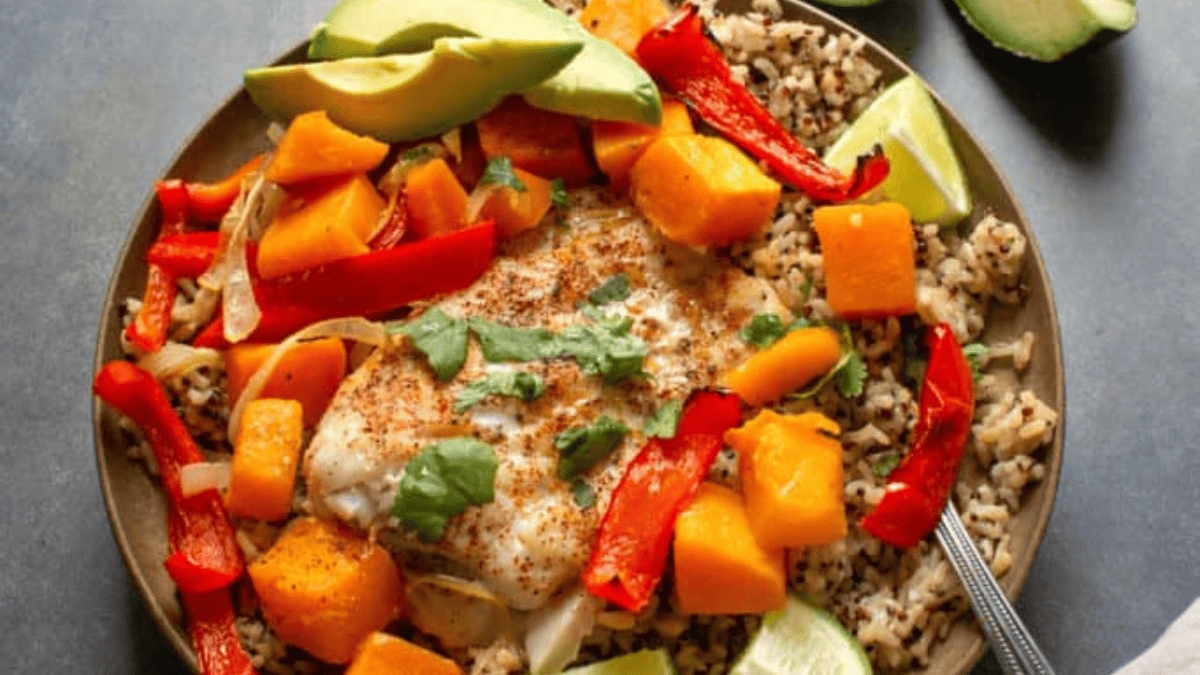 A bowl of baked cod with butternut squash, avocado and lime.