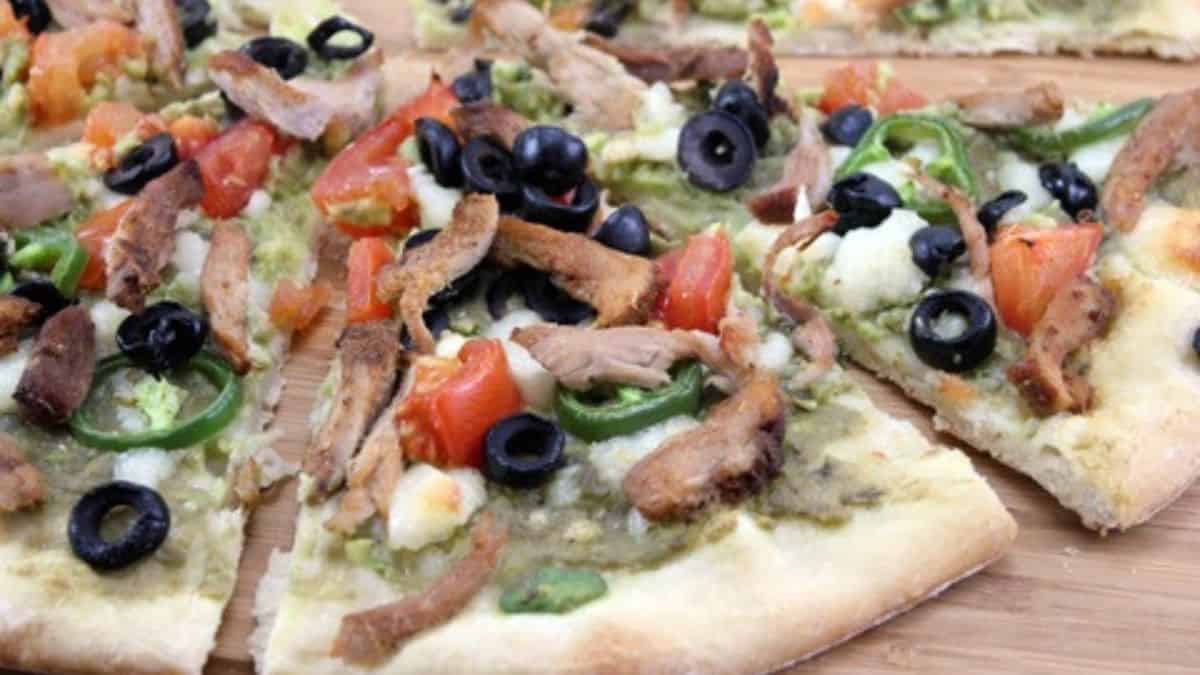 A flatbread with pork, guacamole and olives.